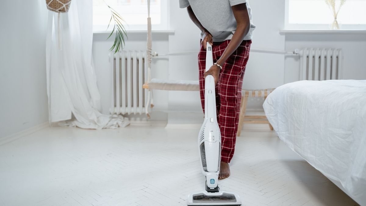 A Man Cleaning Floor With Stick Vacuum