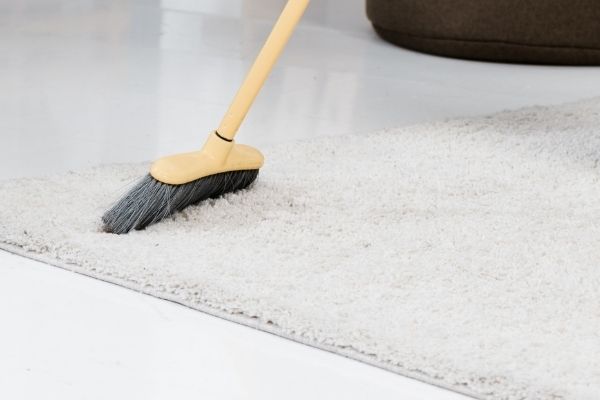 Using Broom To Sweep Dirt From Carpet