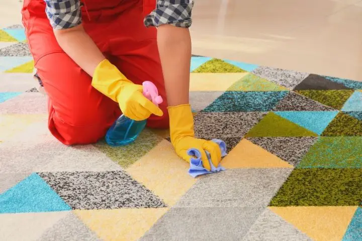 A Woman Is Cleaning A Carpet With Spray